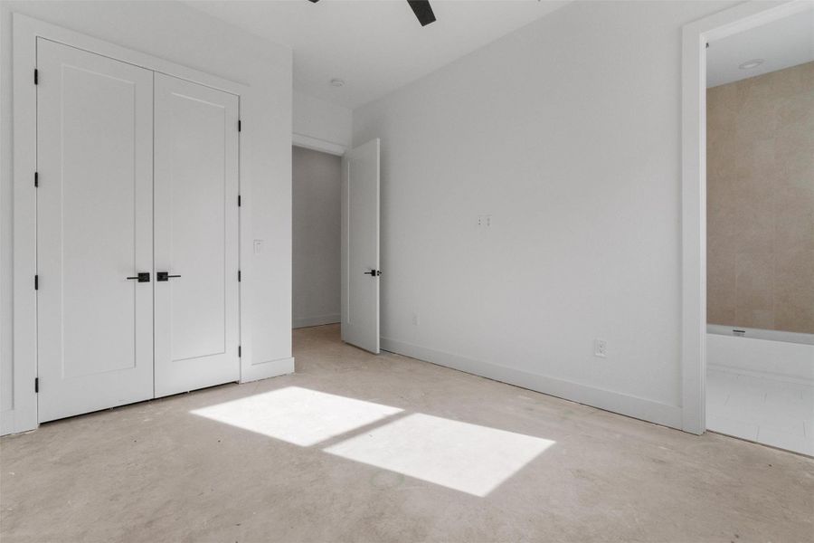 Unfurnished bedroom with ensuite bathroom, concrete flooring, and ceiling fan Unfurnished bedroom with ensuite bathroom, concrete flooring, and ceiling fan