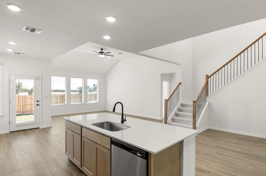 Kitchen with light wood-style floors, open floor plan, stainless steel dishwasher, recessed lighting, and vaulted ceiling