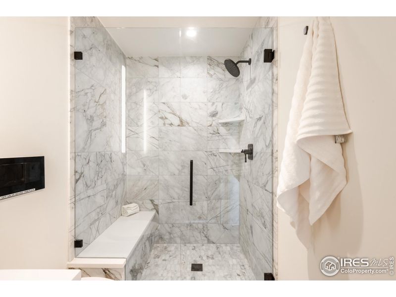 The sleek 3/4 bathroom features a spacious walk-in shower with calacatta marble tile, shared between two additional bedrooms on the third level.