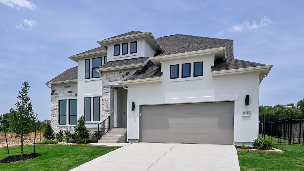 View of front of property featuring stone siding, driveway, a garage, and stucco siding View of front of property featuring stone siding, driveway, a garage, and stucco siding