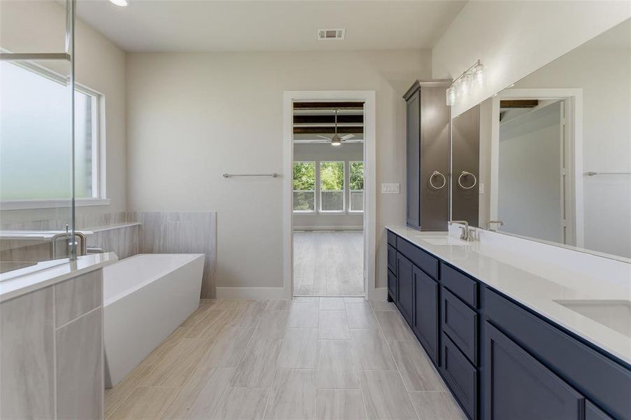 Bathroom featuring a freestanding soaking tub, separate shower with glass enclosure, dual vanity with undermount sinks, and ceramic tile flooring