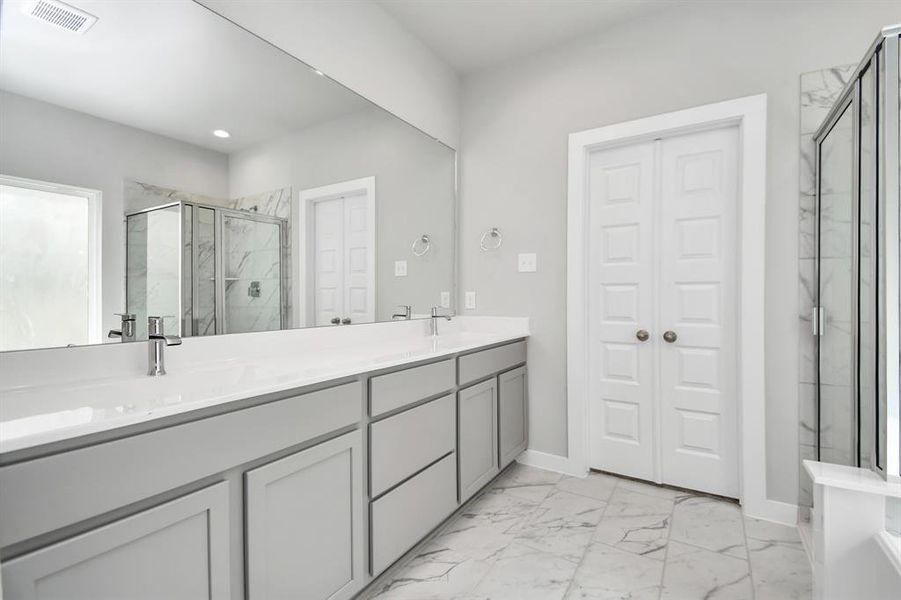 Enjoy the roomy walk-in shower encased in stylish tile, take a moment to unwind in a separate garden tub embellished with custom details, and elevate your daily routine at the refined vanity, now boasting double sinks, light-toned countertops, modern hardware, and bright recessed lights. Sample photo of completed home with similar floor plan. Actual colors and selections may vary.