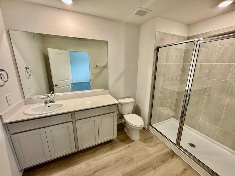 Bathroom featuring a stall shower, vanity, and light wood-style floors