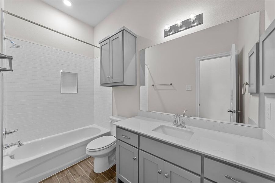 Full bathroom featuring toilet, tiled shower / bath, vanity, and wood-type flooring