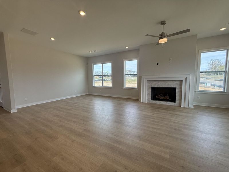 Unfurnished living room featuring a ceiling fan, a brick fireplace, light wood-type flooring, and recessed lighting
