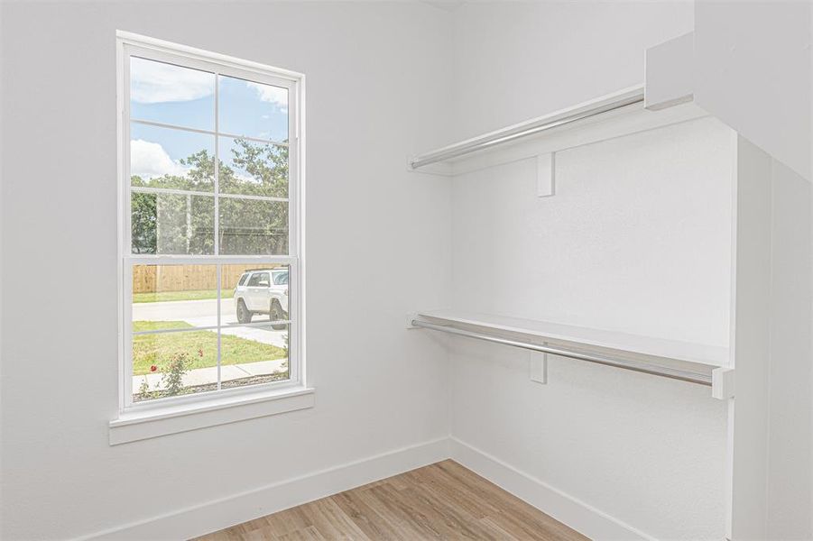 Closet featuring wood-finish flooring, white walls, and a window with grid panes