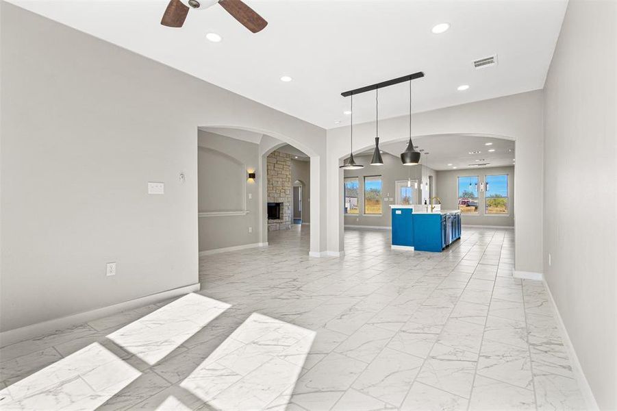 Unfurnished living room featuring light marble finish flooring, arched walkways, recessed lighting, ceiling fan, and a fireplace