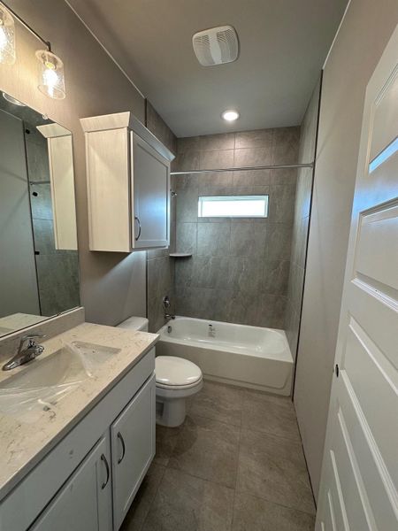 Full bathroom featuring toilet, tiled shower / bath combo, and vanity