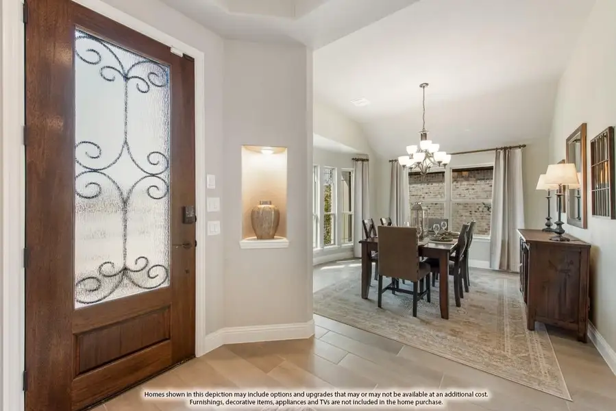 Entryway with wood and glass front door opening to dining room with chandelier and vaulted ceiling