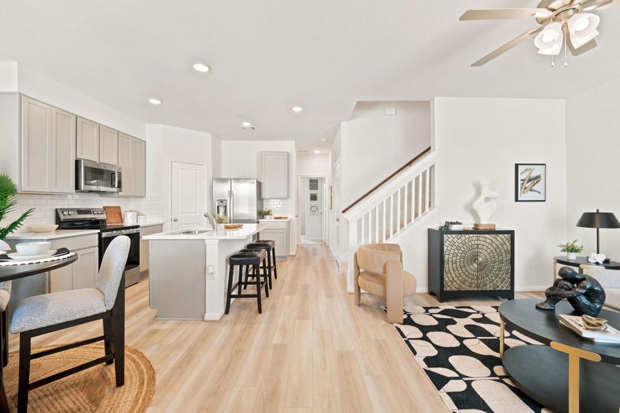 Hardwood floors and clean white walls connect the kitchen and living areas seamlessly.