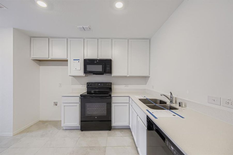 Kitchen featuring light countertops, white cabinets, black appliances, recessed lighting, and open floor plan