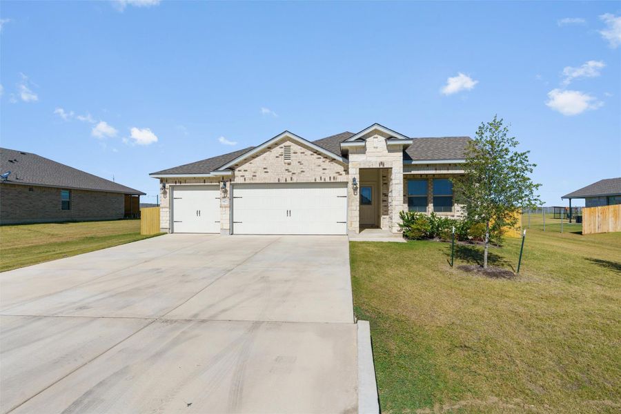 View of front of house featuring an attached garage, driveway, roof with shingles, stone siding, and brick siding