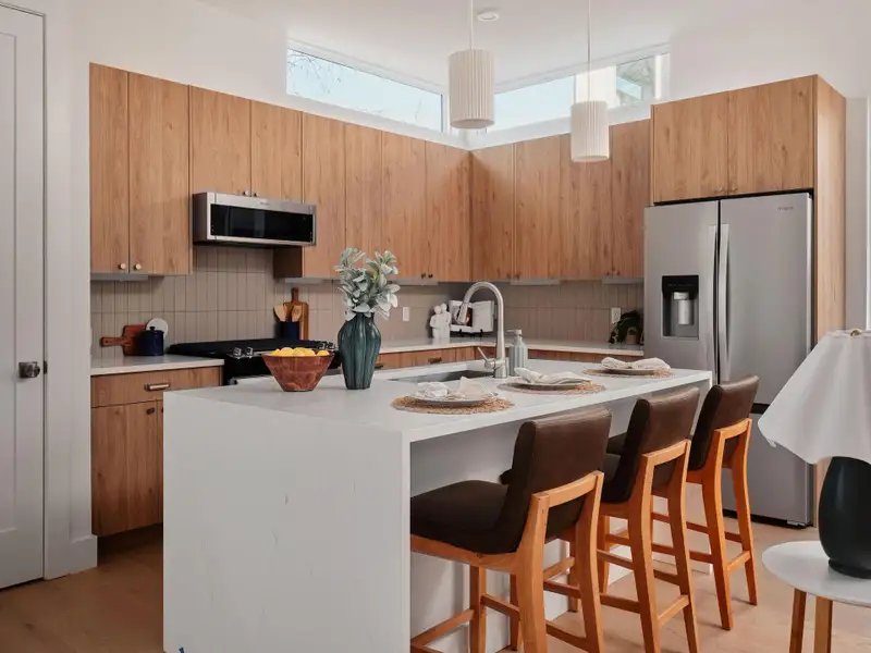 Kitchen with a breakfast bar area, stainless steel appliances, modern cabinets, a kitchen island with sink, and light stone counters