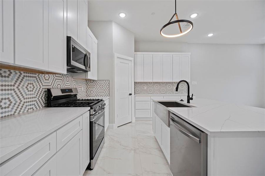 Kitchen featuring marble finish floor, a kitchen island with sink, a sink, light stone counters, and stainless steel appliances