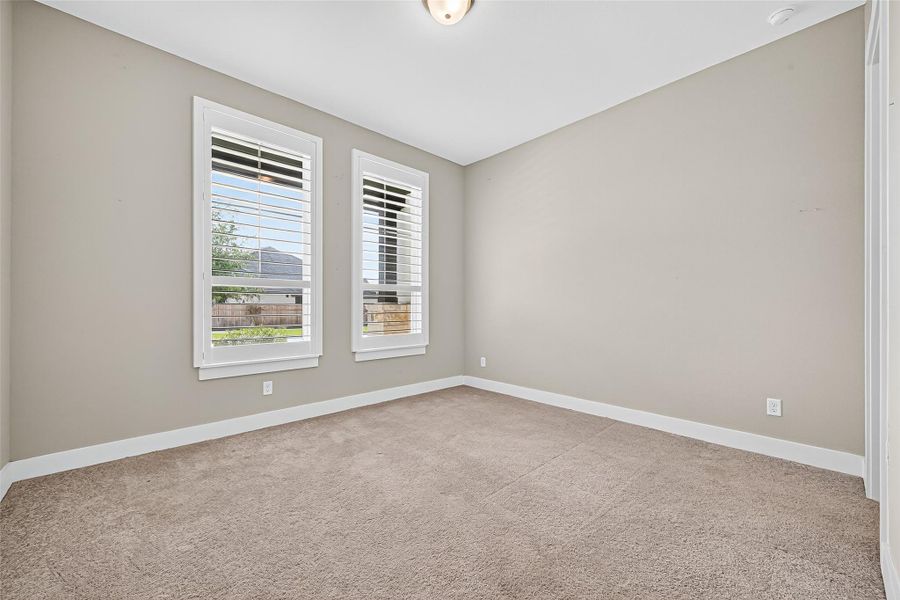 Secondary bedroom downstairs outfitted with plantation shutters.