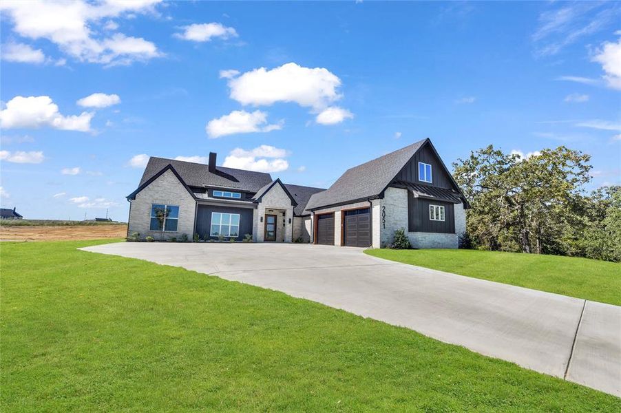 View of front of property featuring a front lawn and a garage