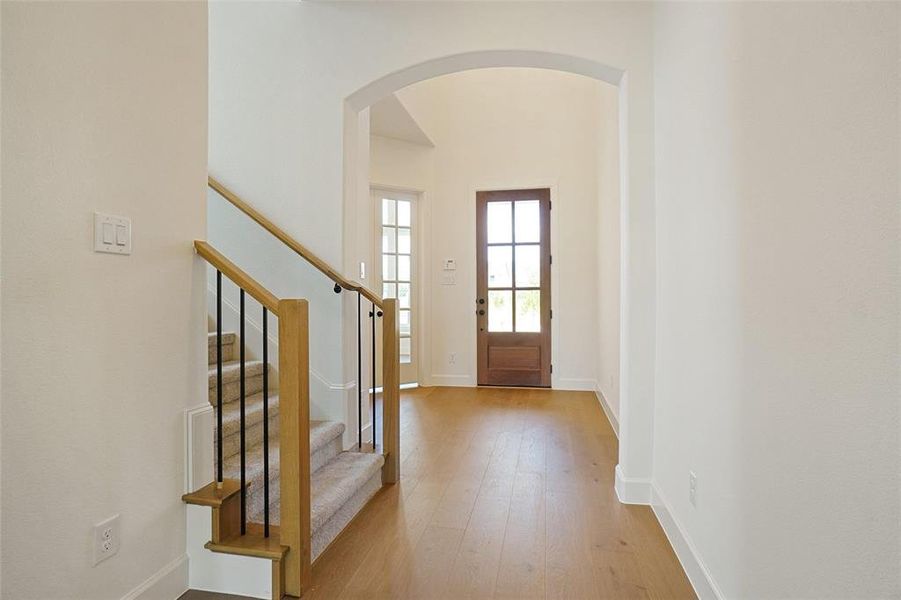 Entryway featuring arched walkways, hardwood / wood-style floors, and stairs Entryway featuring arched walkways, hardwood / wood-style floors, and stairs