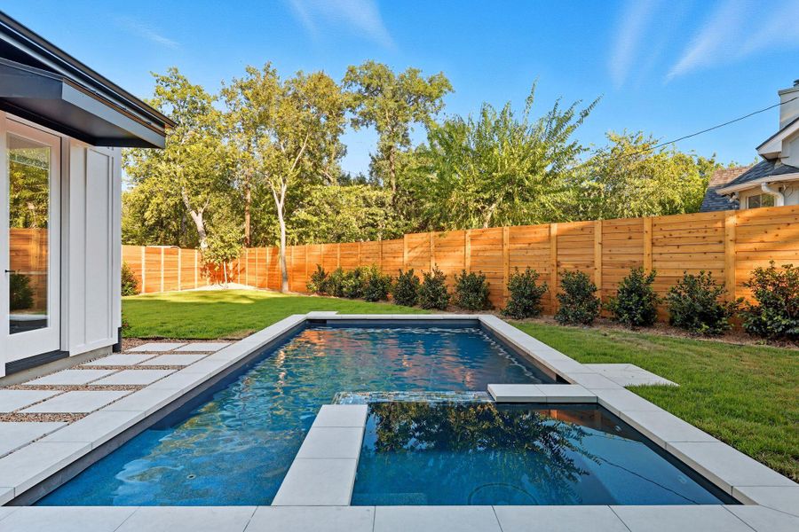 View of pool featuring a fenced backyard, a pool with connected hot tub, and a patio area