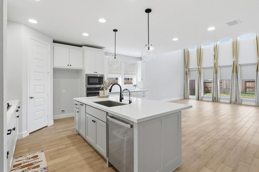 The heart of the home is this beautifully designed gourmet kitchen, where a generous quartz island overlooks the dramatic two-story family room. Walls of windows flood the space with natural light, creating an open and inviting atmosphere perfect for gathering and entertaining.
