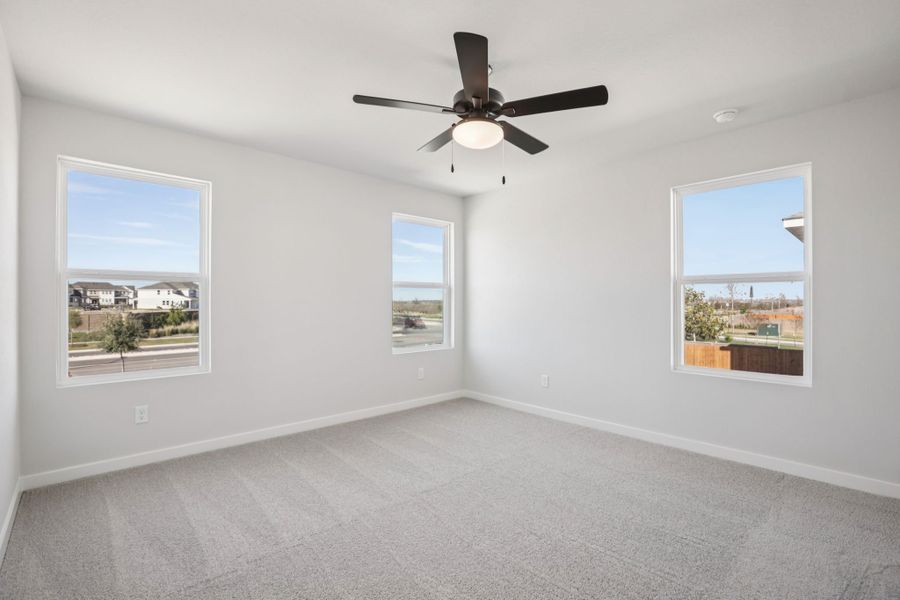 A room with a ceiling fan and windows.