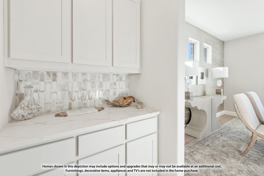 Wet bar or butler's pantry with white cabinets, marble countertop, and decorative tile backsplash, with a sitting area visible beyond. Wet bar or butler's pantry with white cabinets, marble countertop, and decorative tile backsplash, with a sitting area visible beyond.