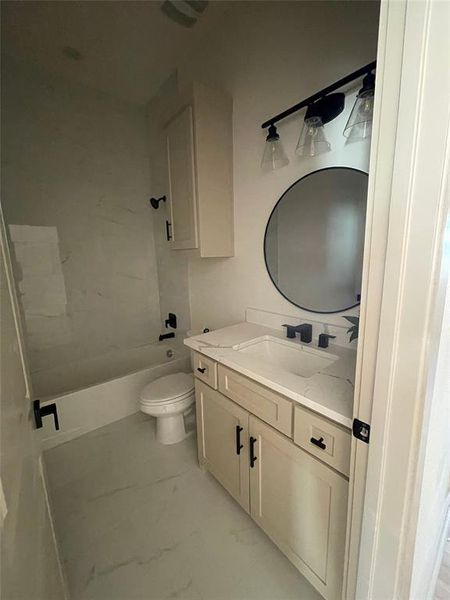 Full secondary bathroom featuring tiled shower / bath, vanity, and toilet