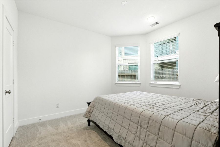 The first floor bedroom features largewindows and plush carpet. The first floor bedroom features largewindows and plush carpet.