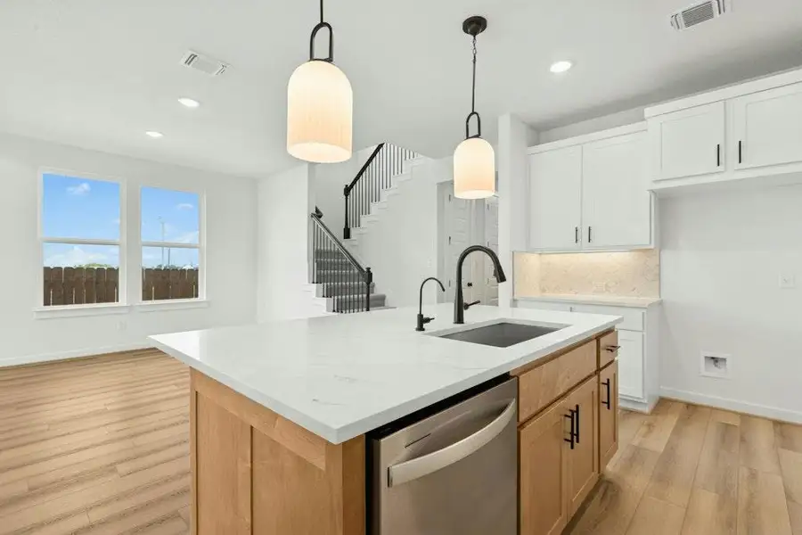 Kitchen featuring light wood-type flooring, dishwasher, light stone counters, pendant lighting, and recessed lighting
