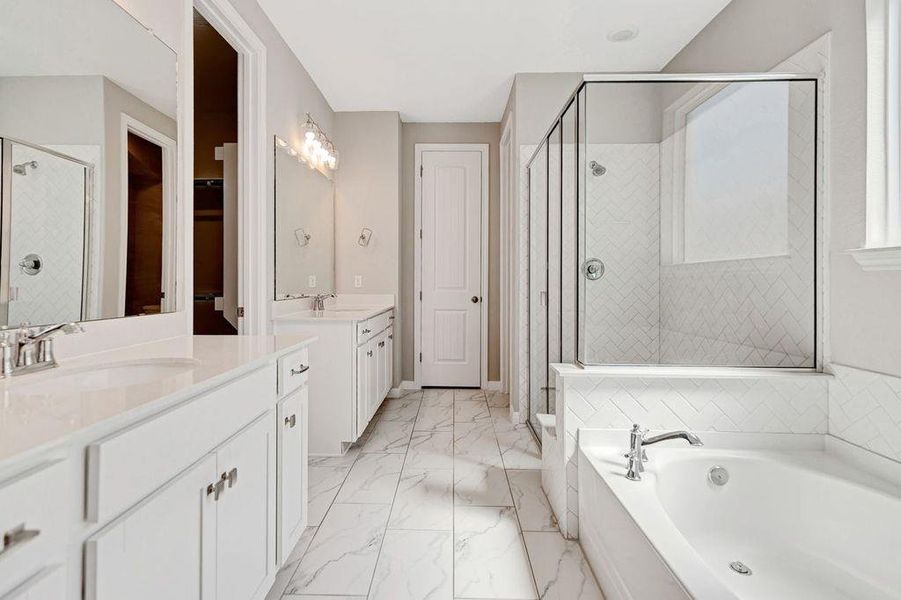 Full bathroom featuring a shower stall, a bath, two vanities, and light marble finish floors Full bathroom featuring a shower stall, a bath, two vanities, and light marble finish floors