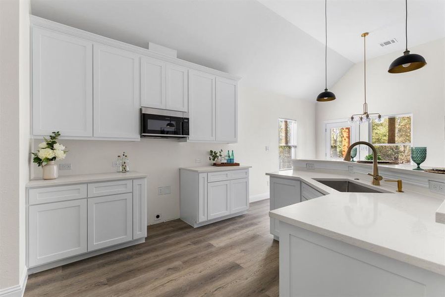 Kitchen with white cabinetry, hardwood / wood-style flooring, sink, and hanging light fixtures