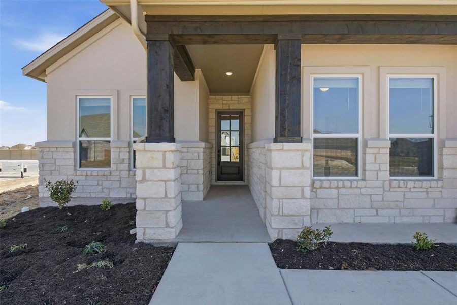 Covered entryway featuring light-toned stone and stucco exterior