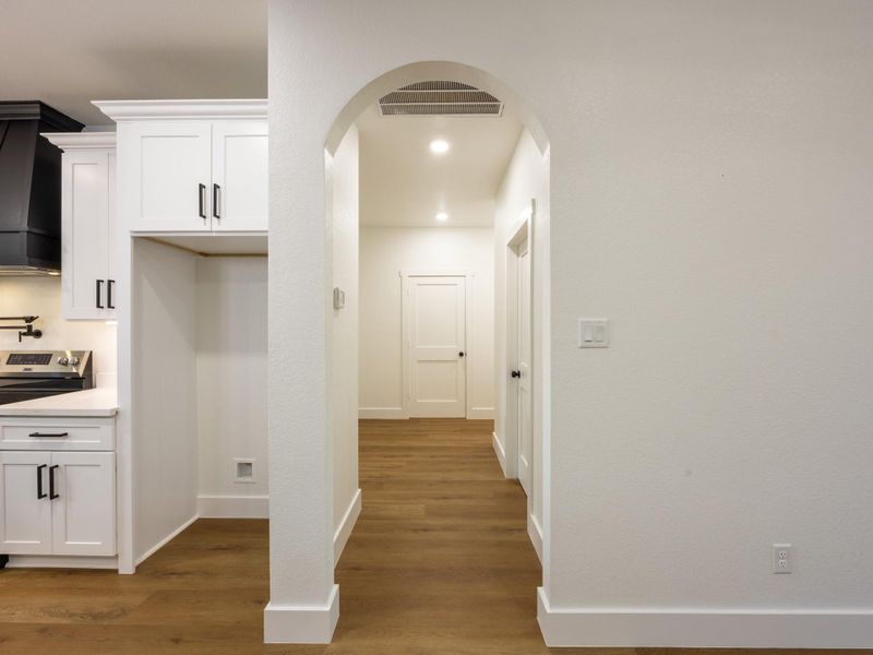 A graceful arched entry leads from the kitchen into the bedroom wing, adding architectural charm while maintaining the home’s clean, cohesive flow. A graceful arched entry leads from the kitchen into the bedroom wing, adding architectural charm while maintaining the home’s clean, cohesive flow.