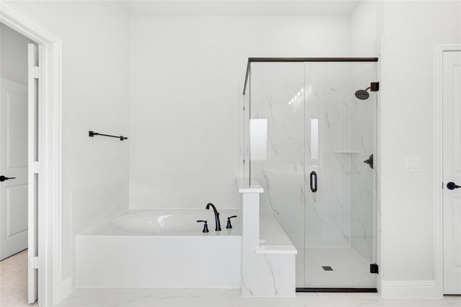 White bathroom with soaking tub, glass-enclosed shower, marble tile walls, and matte black fixtures White bathroom with soaking tub, glass-enclosed shower, marble tile walls, and matte black fixtures