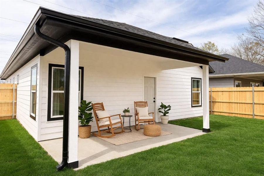 Rear view of house featuring a patio and a shingled roof
