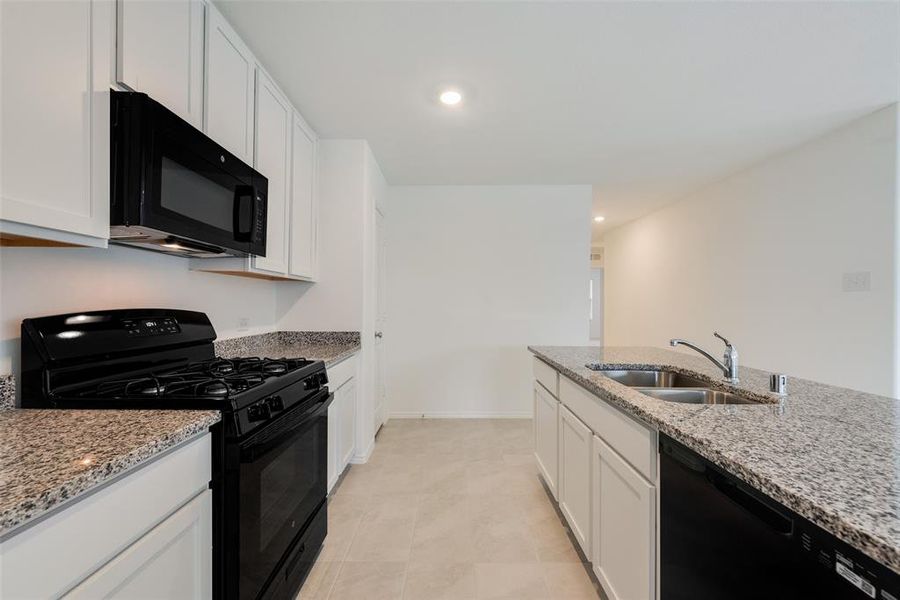 Kitchen featuring sink, black appliances, white cabinetry, and light stone counters