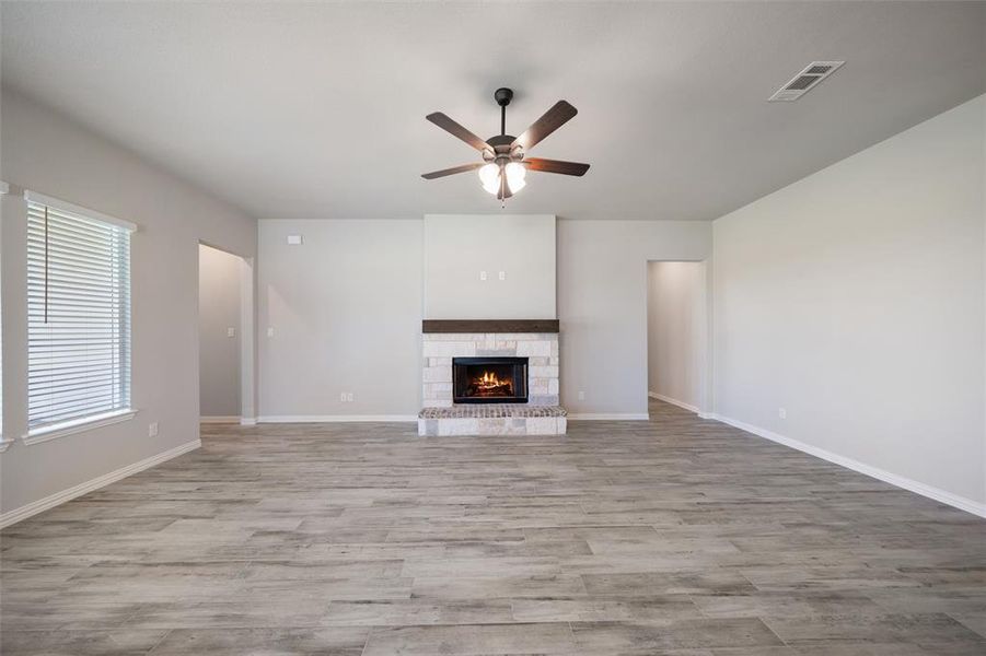 Unfurnished living room featuring wood finished floors, a fireplace, and a ceiling fan Unfurnished living room featuring wood finished floors, a fireplace, and a ceiling fan