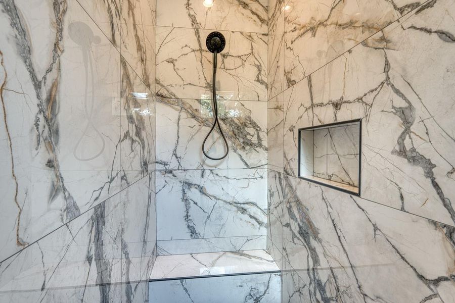 Indulge in this marble-clad shower with recessed lighting and a built-in niche for bathing essentials.