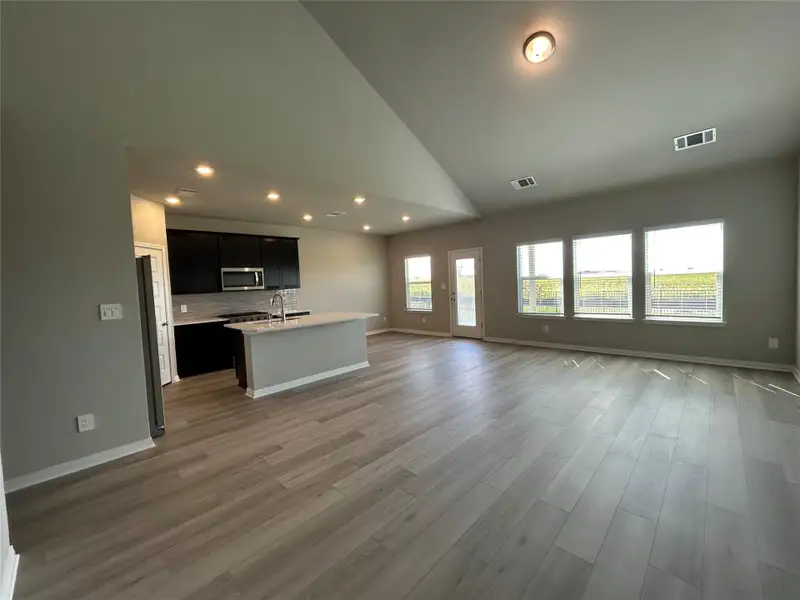 Unfurnished living room featuring recessed lighting, wood finished floors, and high vaulted ceiling