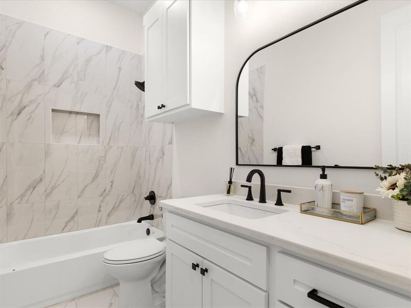 Bathroom featuring a white vanity with slab countertop, undermount sink, and matte black fixtures