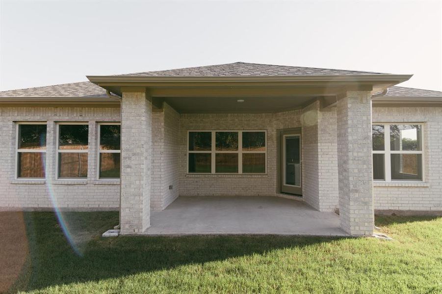 Rear view of house featuring a lawn and a patio area