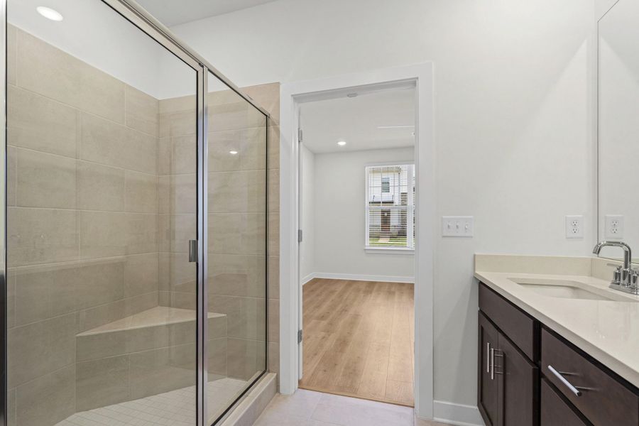 Shower enclosure featuring a glass door, light-toned tile surround, and a built-in bench