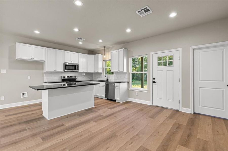 Kitchen featuring white cabinets, tasteful backsplash, recessed lighting, light wood finished floors, and appliances with stainless steel finishes Kitchen featuring white cabinets, tasteful backsplash, recessed lighting, light wood finished floors, and appliances with stainless steel finishes