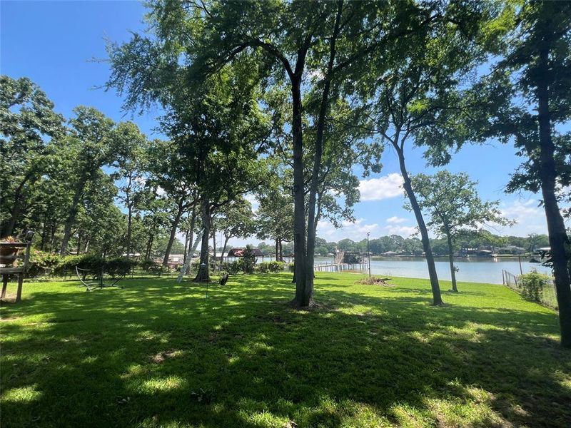 Expansive grassy lawn bordered by mature trees, leading to waterfront access