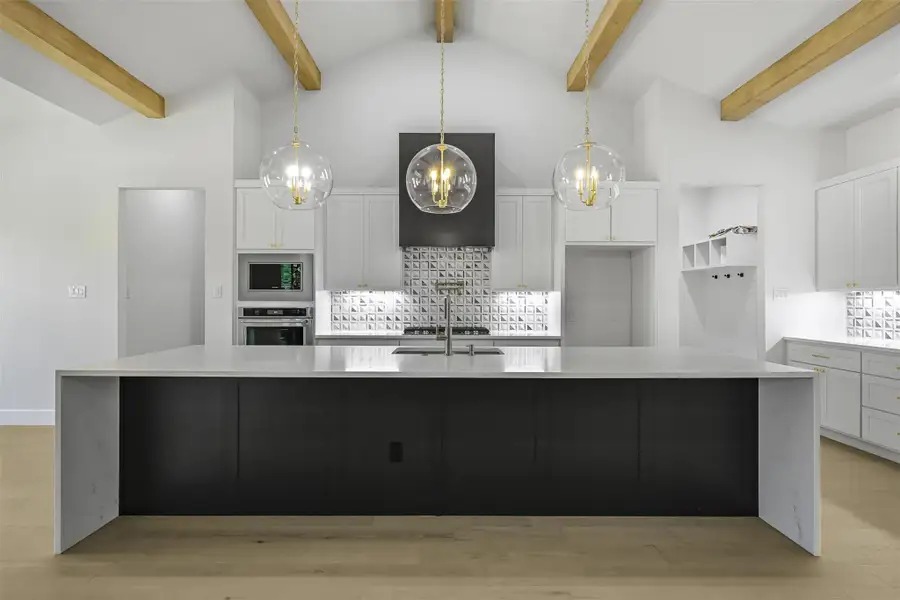 Kitchen featuring tasteful backsplash, white cabinets, a chandelier, light wood finished floors, and light countertops