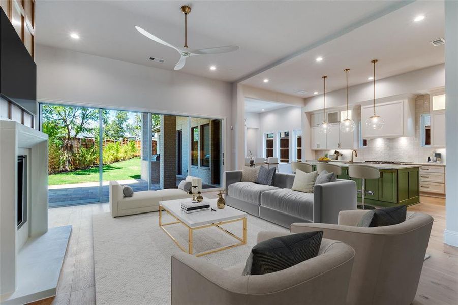 Living room featuring light wood-type flooring, recessed lighting, ceiling fan, a fireplace with raised hearth, and a towering ceiling Living room featuring light wood-type flooring, recessed lighting, ceiling fan, a fireplace with raised hearth, and a towering ceiling