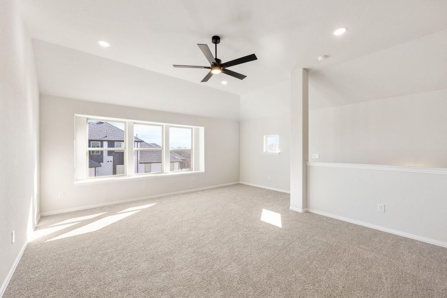 Empty room with carpet flooring, vaulted ceiling, black ceiling fan, and large windows