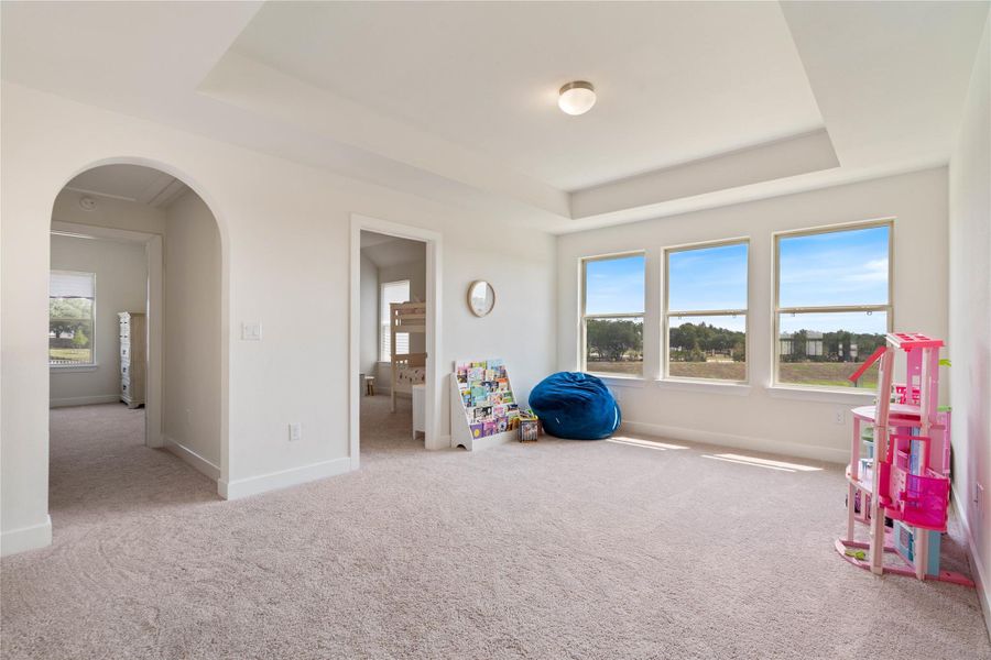 A roomy upstairs den featuring great natural light and a high tray ceiling.