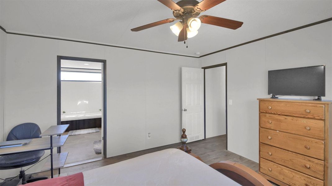 Bedroom featuring an office area, a ceiling fan, ornamental molding, connected bathroom, and wood finished floors
