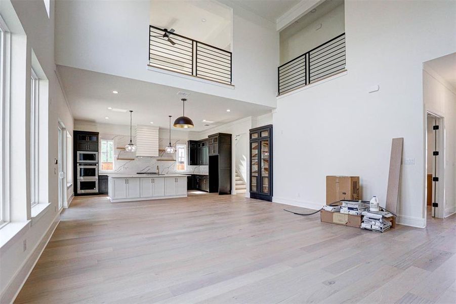 Living room featuring crown molding, sink, light wood-type flooring, and a high ceiling