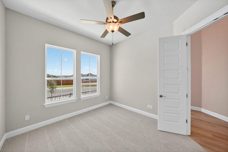 Empty room featuring light carpet and ceiling fan Empty room featuring light carpet and ceiling fan